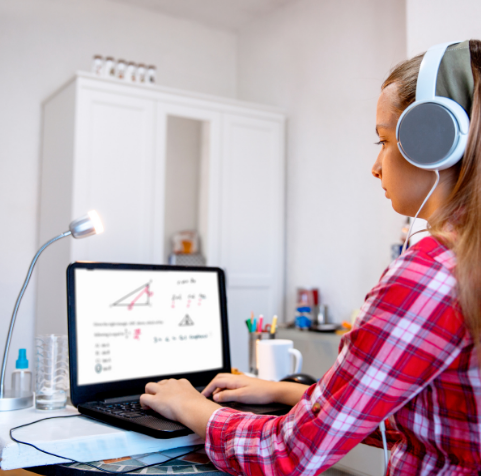 Une étudiante suit un cours de mathématiques depuis son bureau, casque sur les oreilles
